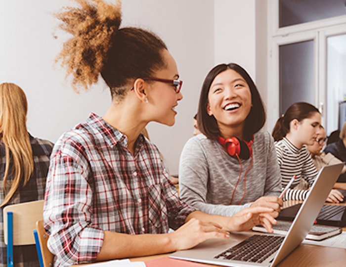 Young women on laptops smiling