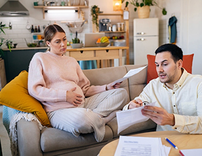 a pregnant woman and a man in their living room reviewing finances