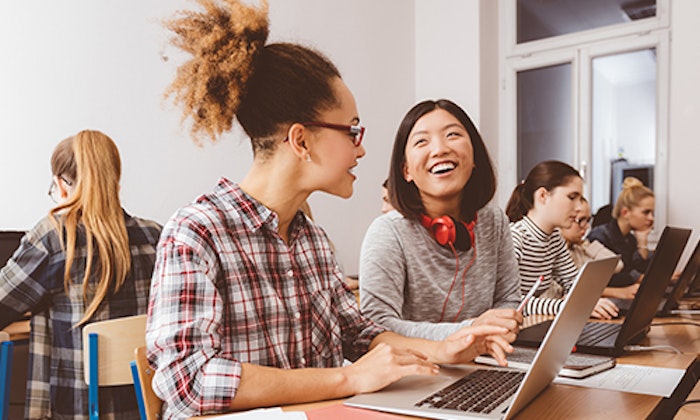 Young women on laptops smiling